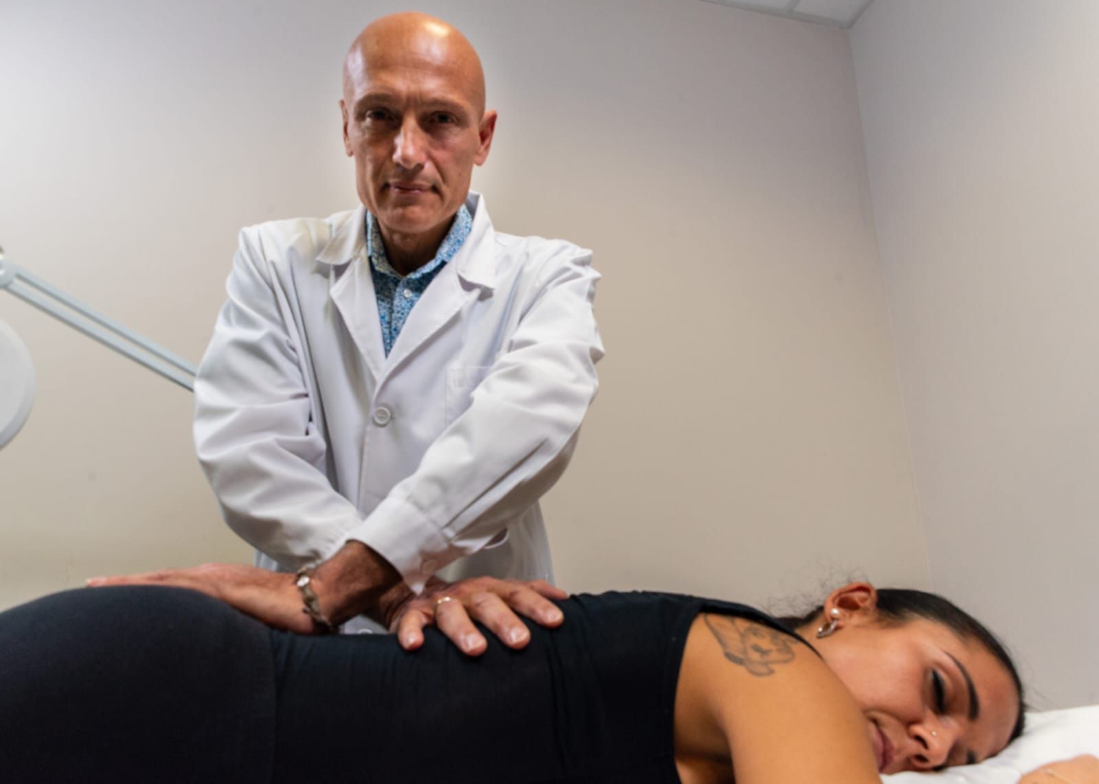Massage therapist giving a shoulder massage, making a heart shape with hands.