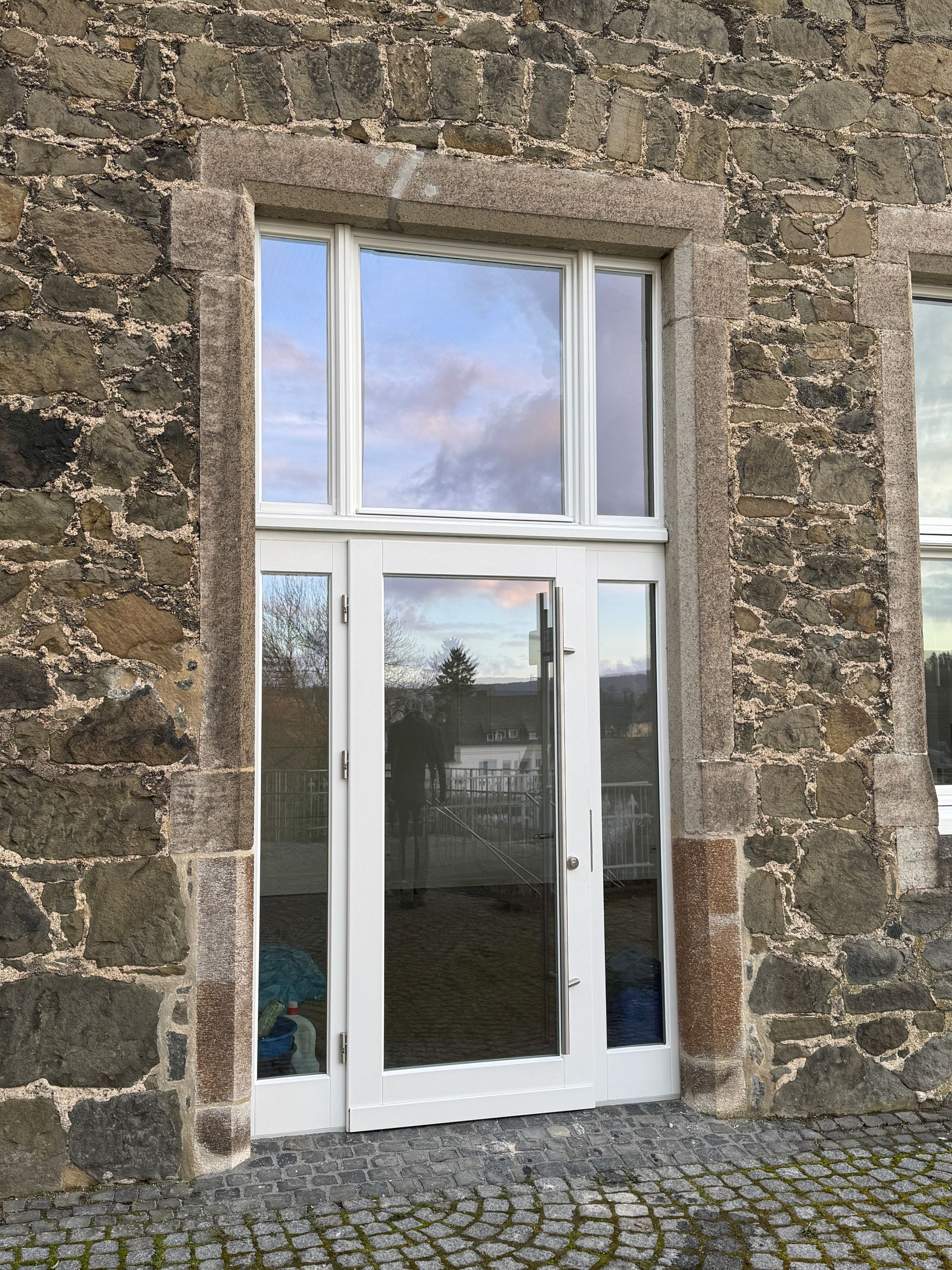 Eine weiße Tür mit Glaseinsätzen, eingefasst in einen rustikalen Steinrahmen.