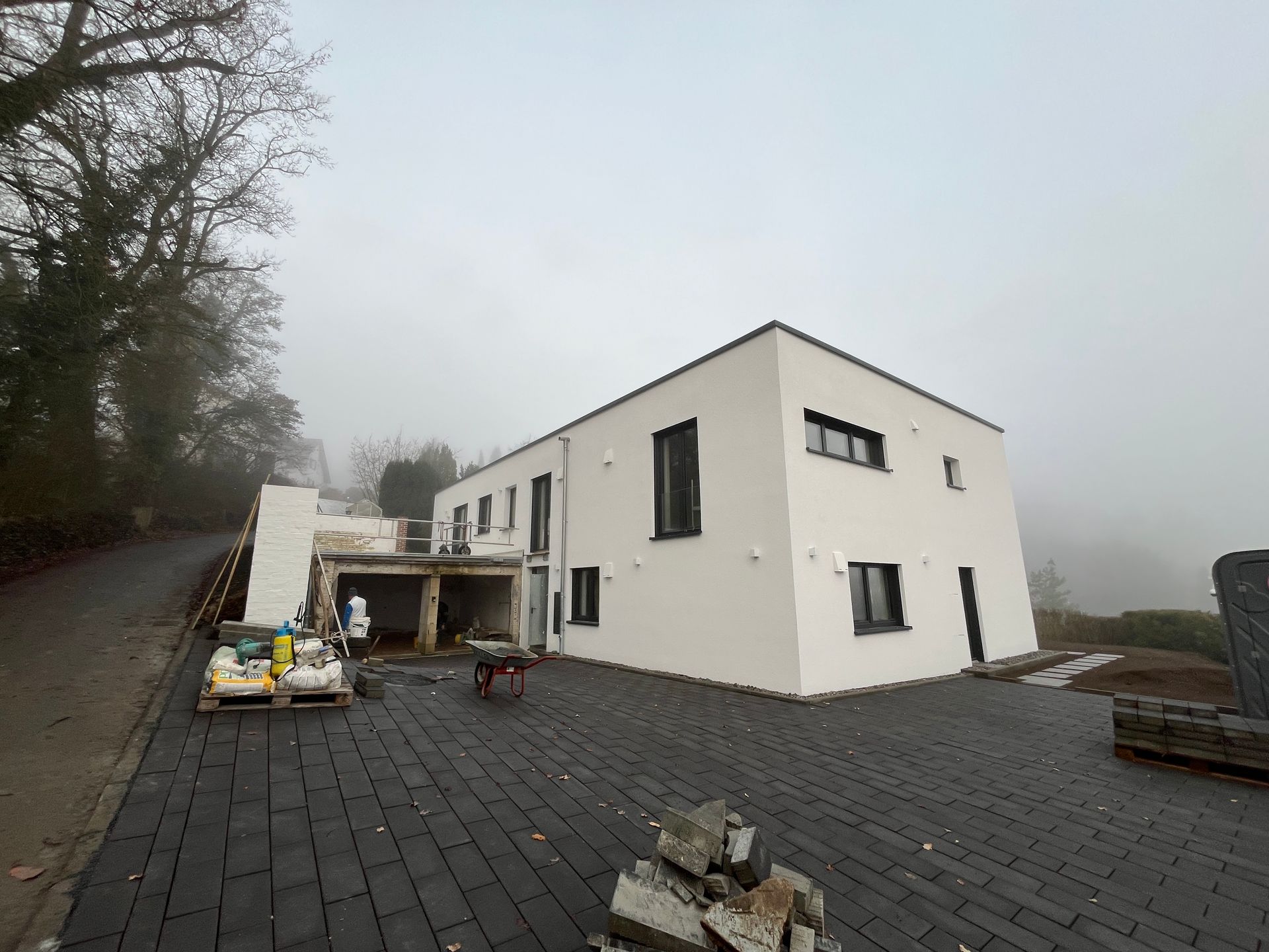 Die Fassade eines modernen, weißen Hauses mit Flachdach an einem nebligen Tag; 