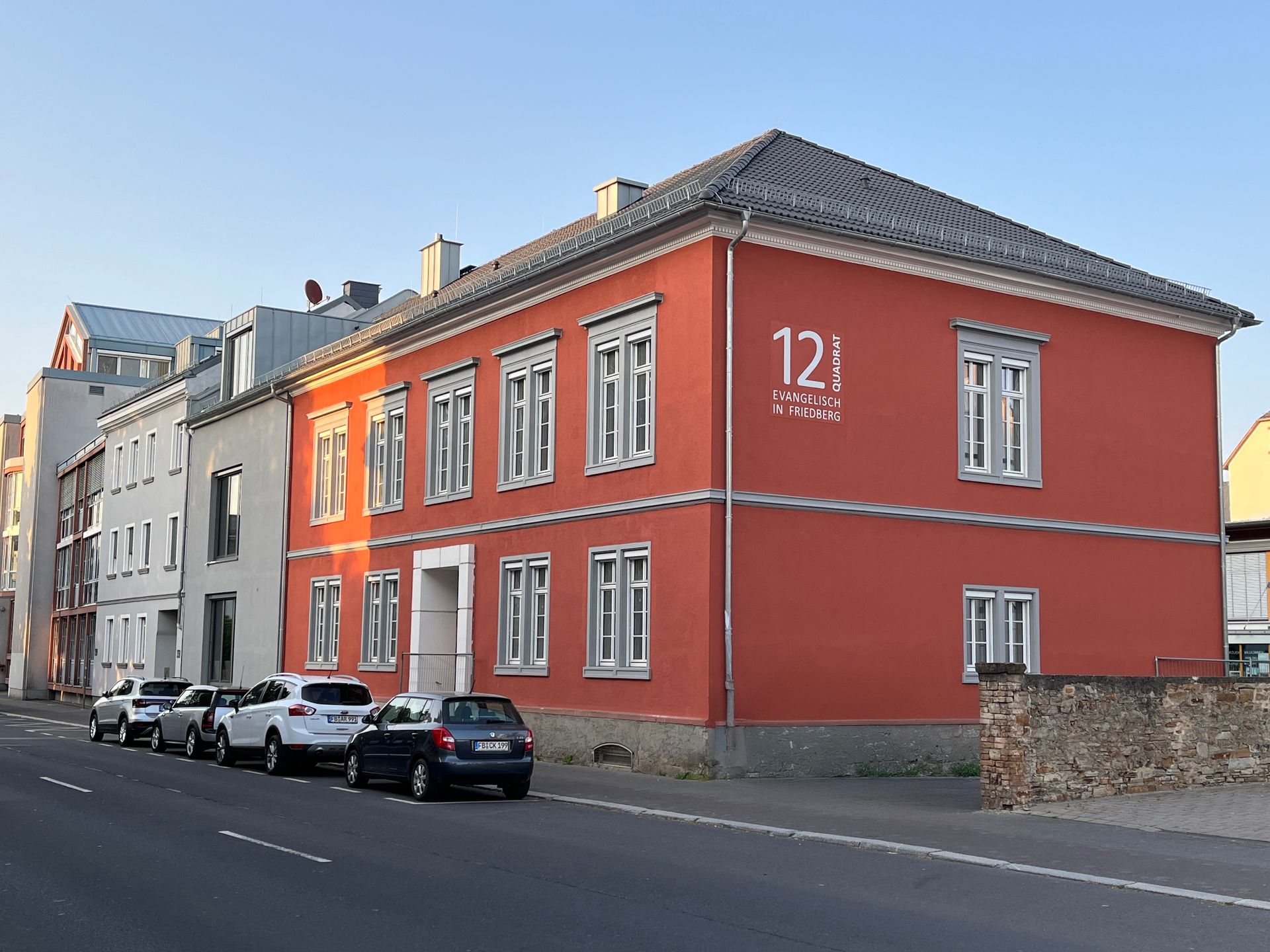 Ein zweistöckiges, rotes Gebäude mit der Nummer „12“ an der Seite, gelegen an einer Straße