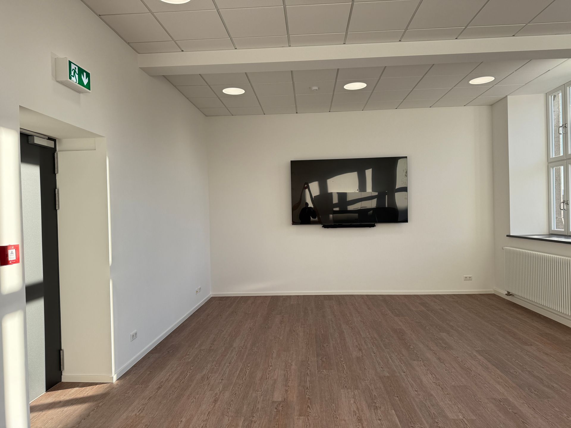 Ein sauberes, leeres Büro oder ein Besprechungsraum mit weißen Wänden, Holzbodenoptik,