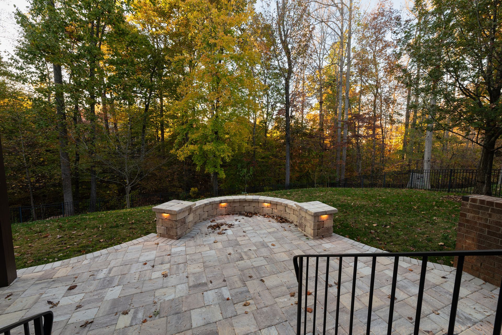 a patio with a bench and trees in the background .