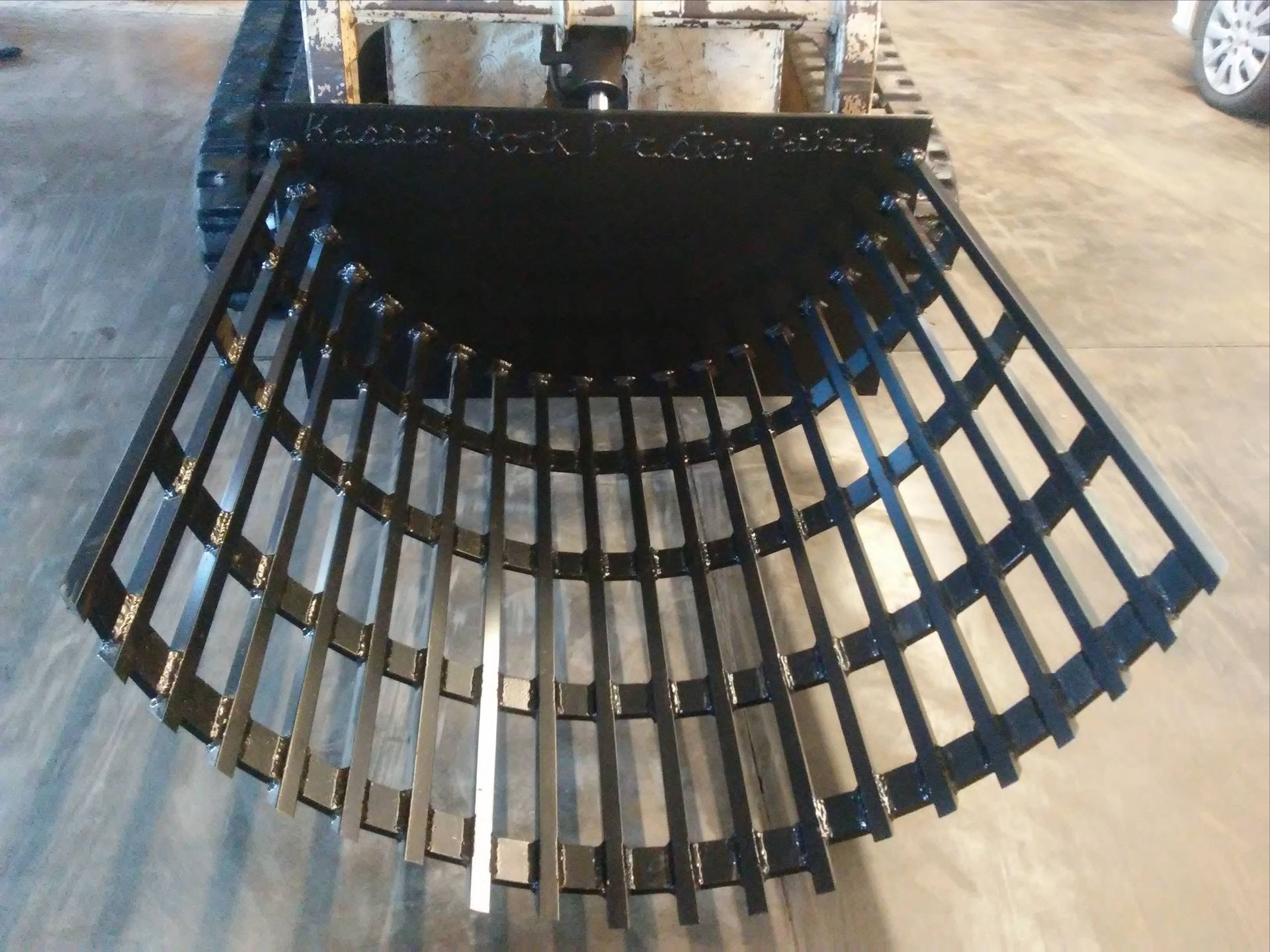 Black skid steer root grapple bucket with curved teeth.