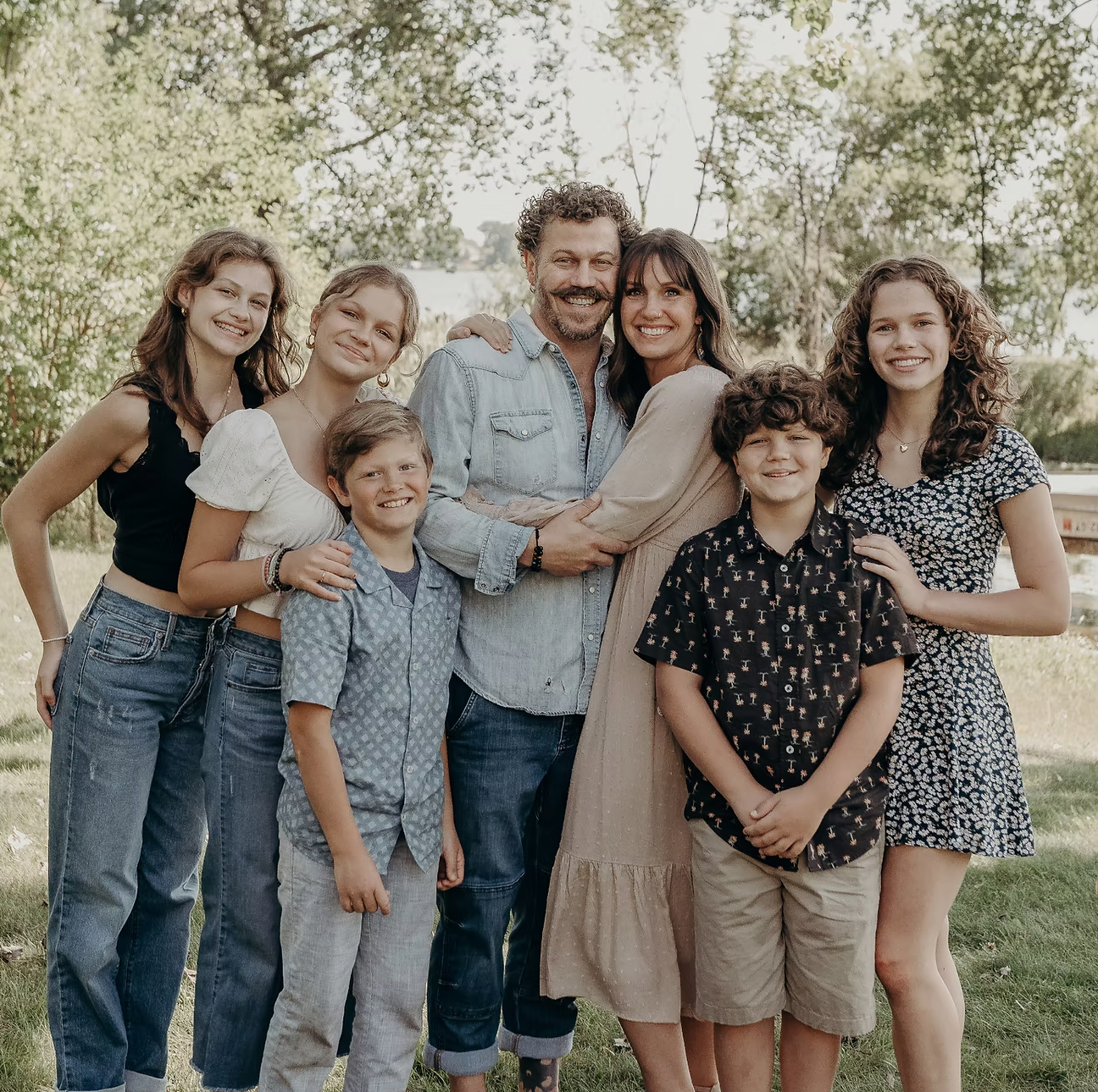 A group of people are posing for a picture together in a park.