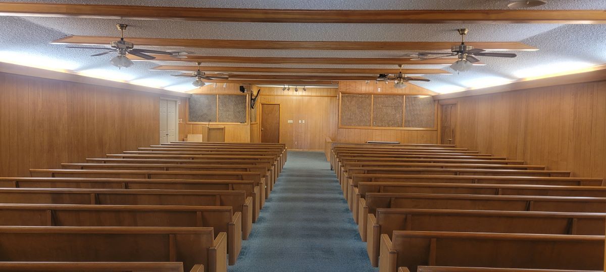 A church with rows of wooden benches and a blue carpet.