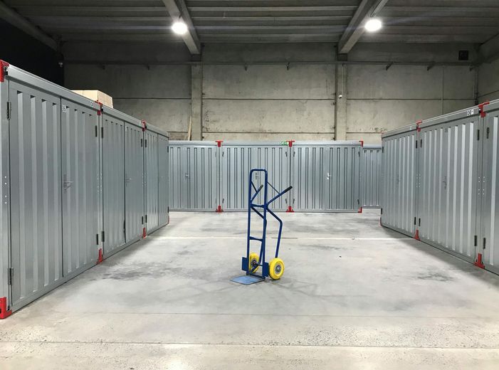A blue hand truck is sitting in the middle of a warehouse.