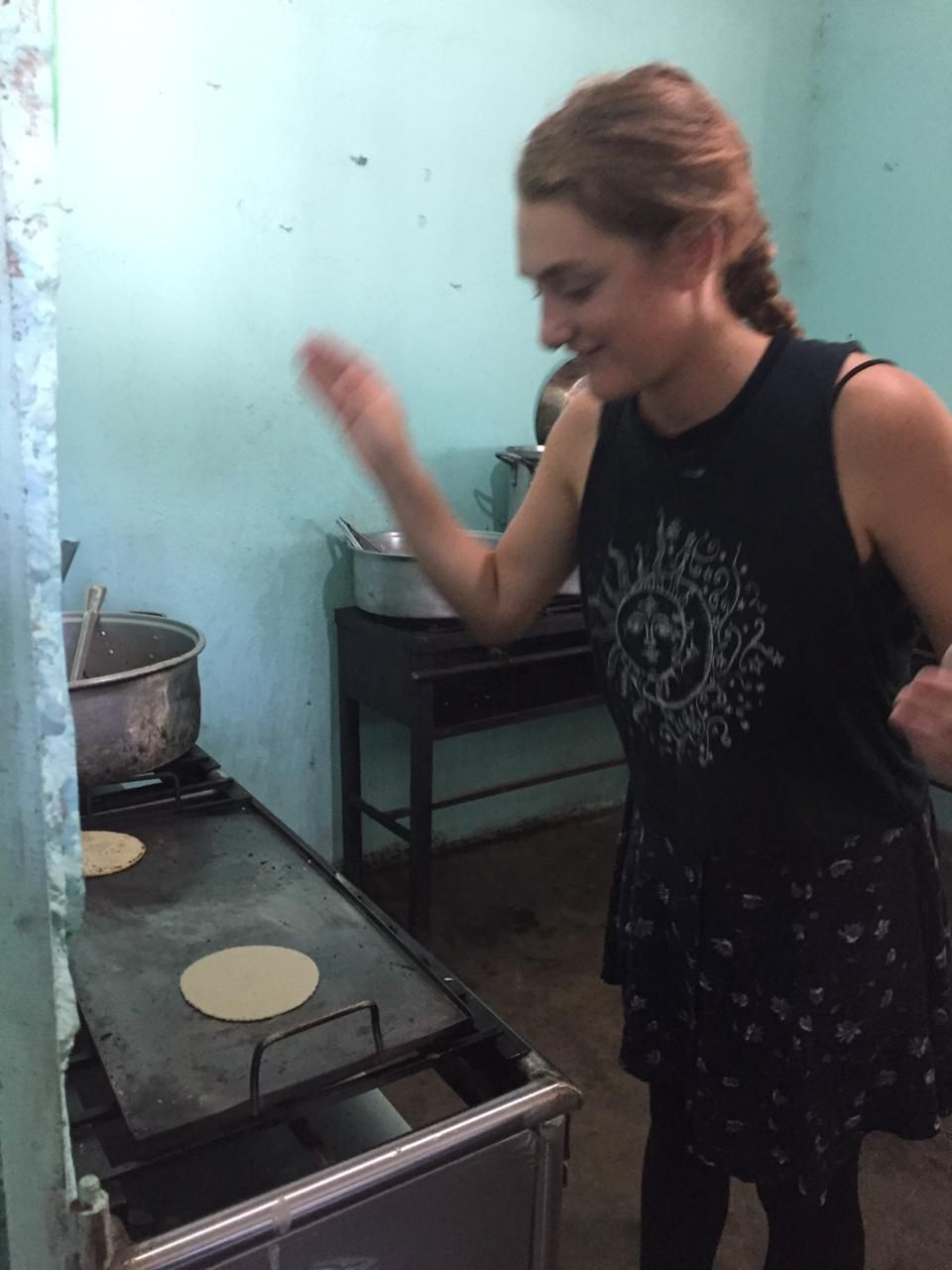 A woman standing in front of a stove with tortillas on it