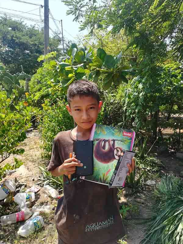 A young boy is holding a book and a cell phone.
