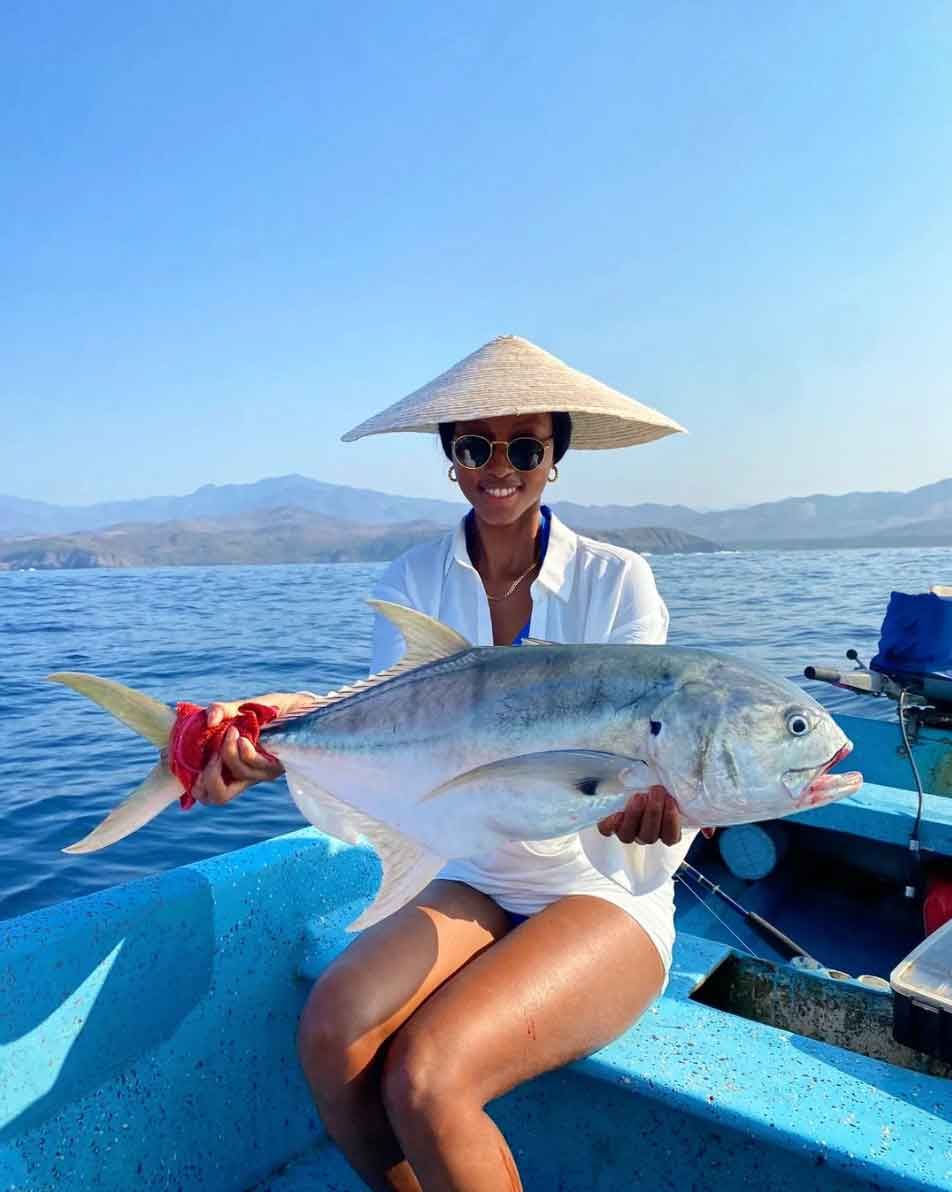 A woman is sitting on a boat holding a large fish.