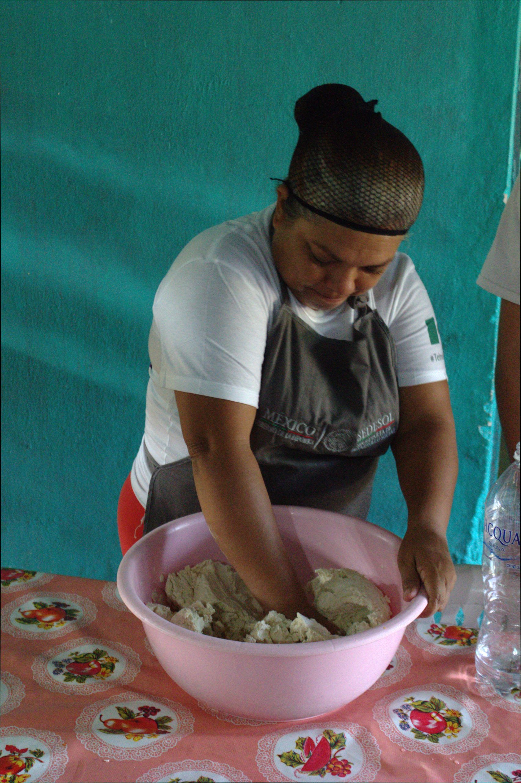 A woman is kneading dough in a pink bowl