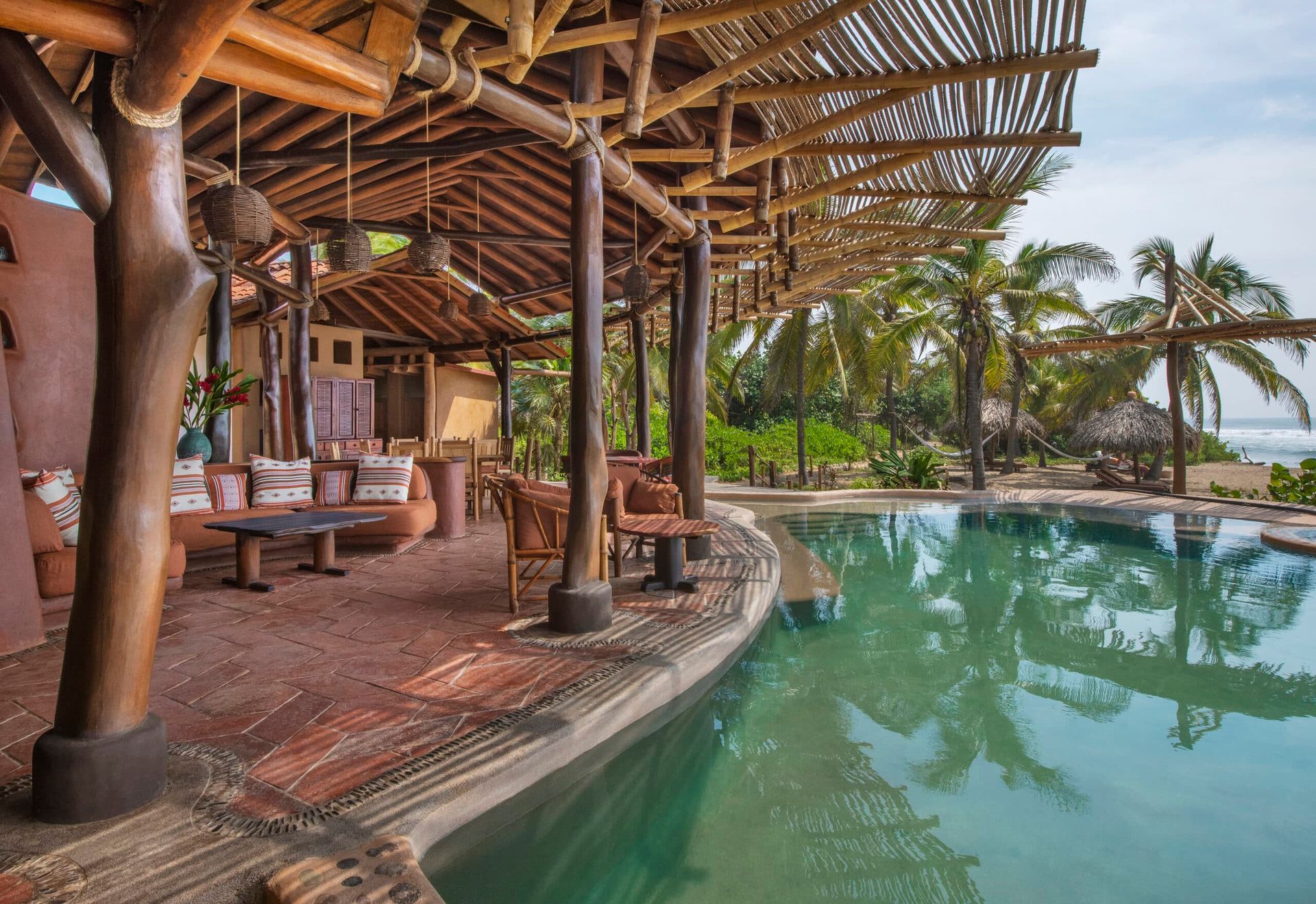 A large swimming pool surrounded by palm trees and a wooden structure.