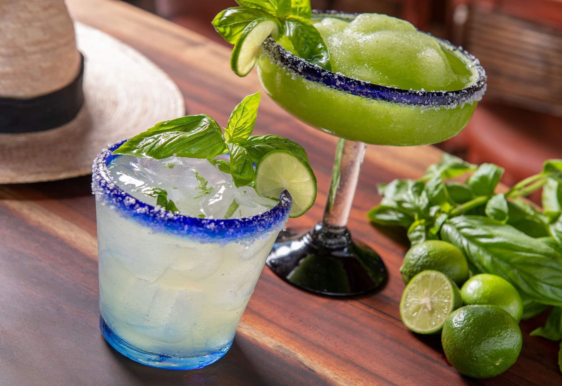 Two margaritas are sitting on a wooden table.