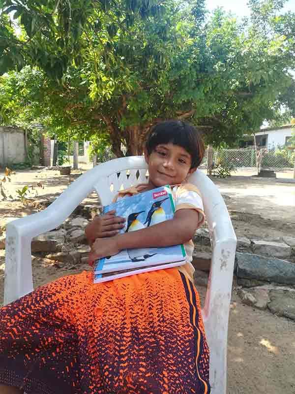 A young boy is sitting in a chair holding a book.