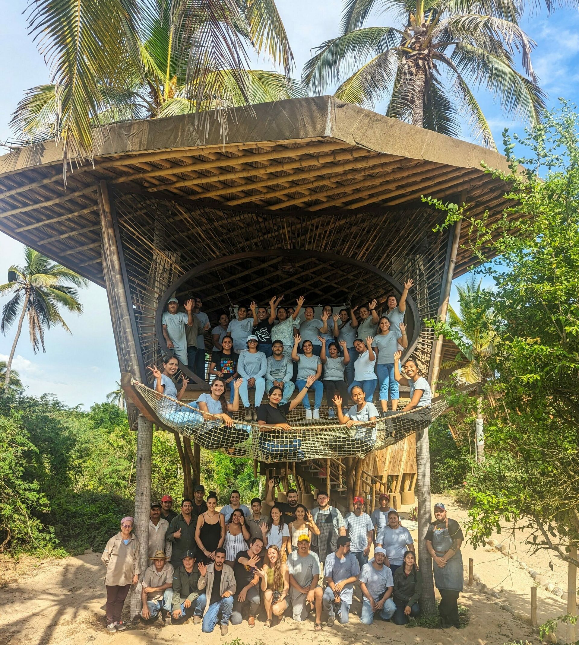 A group of people are posing for a picture in front of a hut.