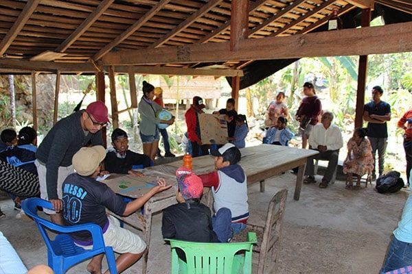 A group of people are gathered around a table with one man wearing a shirt that says mira