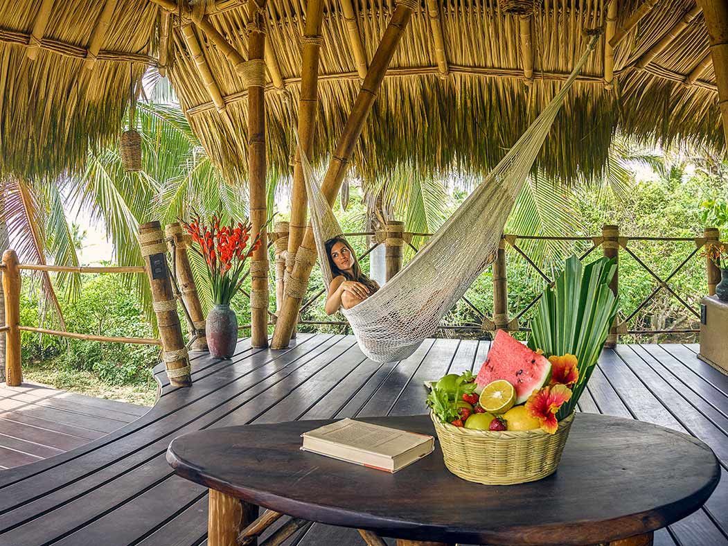 A woman is laying in a hammock on a wooden deck.