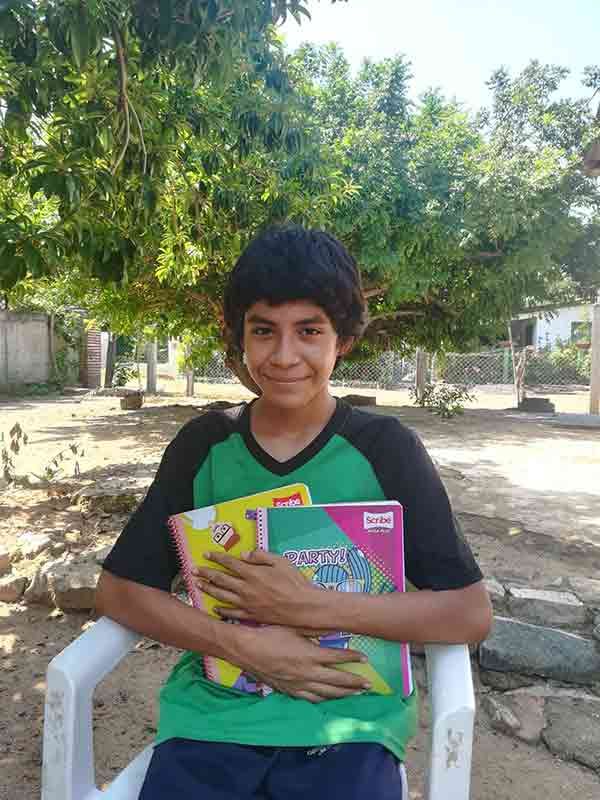 A young boy is sitting in a chair holding books.