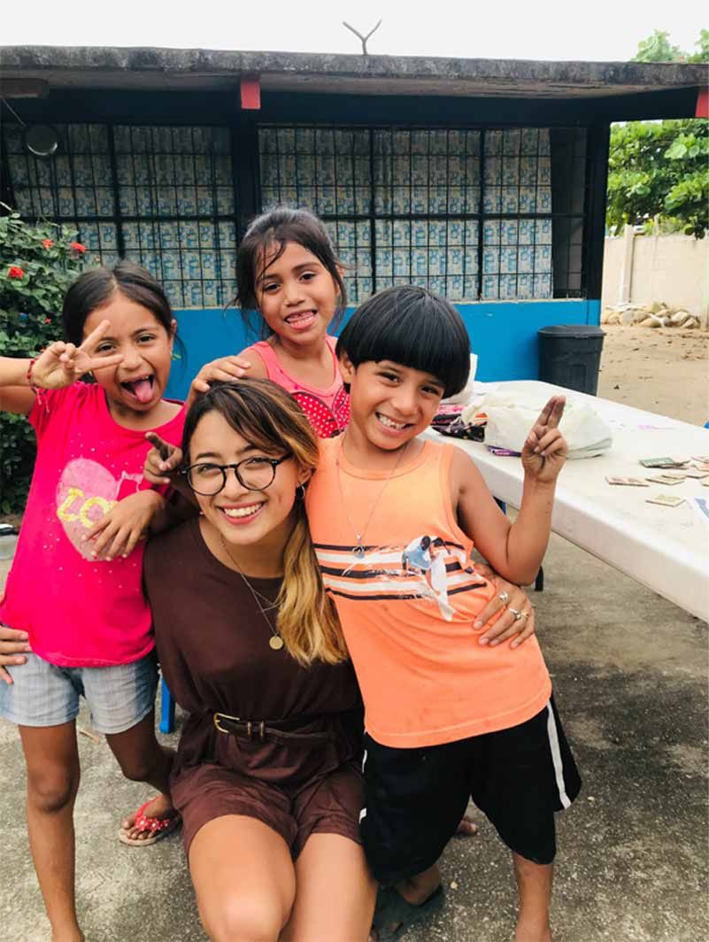 A woman is posing for a picture with three children.