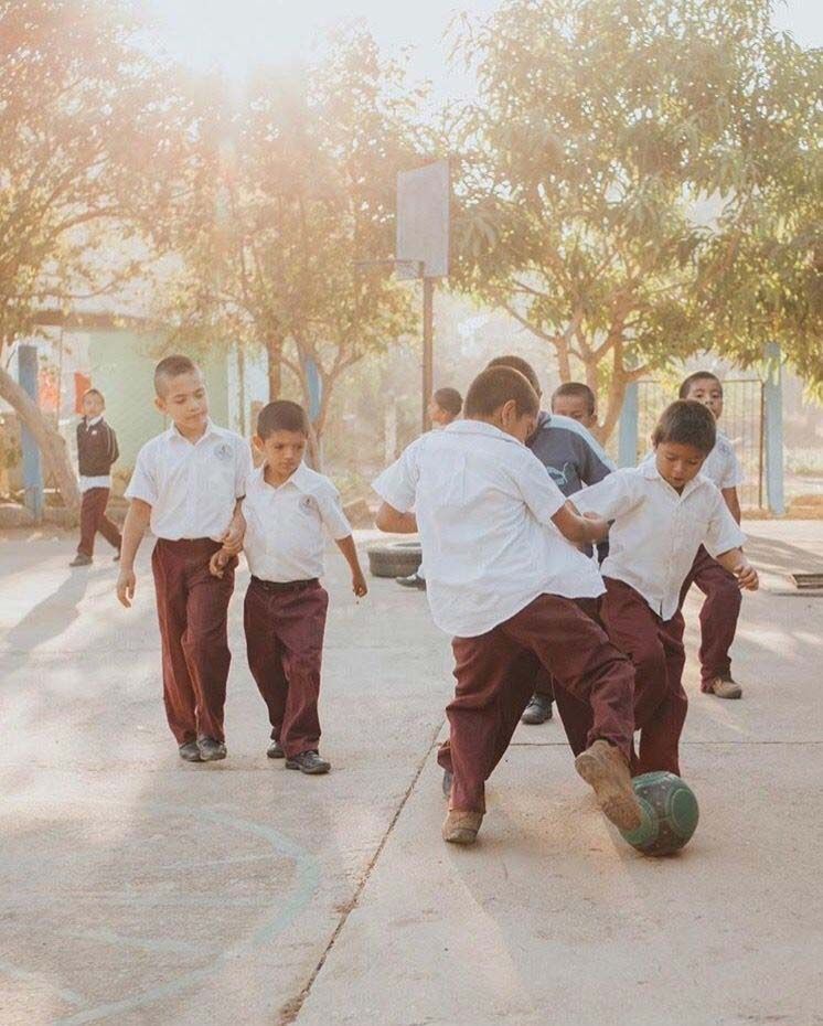 A group of children are playing soccer on a sidewalk.