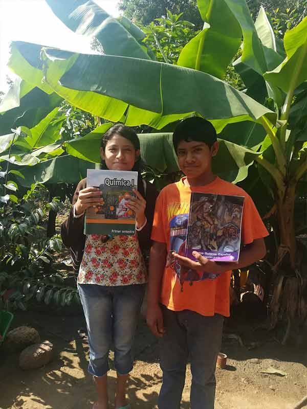 A boy and a girl holding books in front of a banana tree