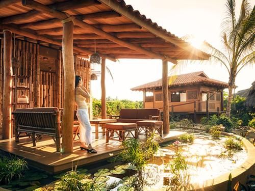 A woman is standing on a porch in front of a wooden house.