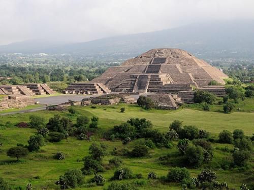 A large pyramid is sitting in the middle of a grassy field.