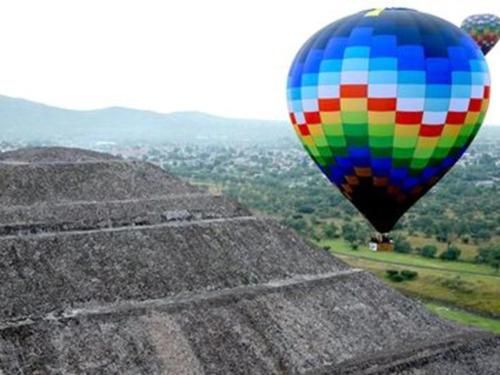A colorful hot air balloon is flying over a pyramid