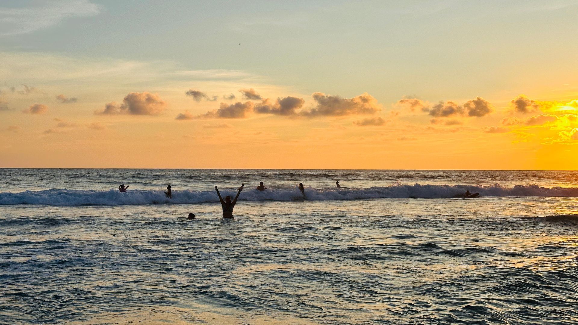 A woman is standing on a sandy beach looking at the ocean.