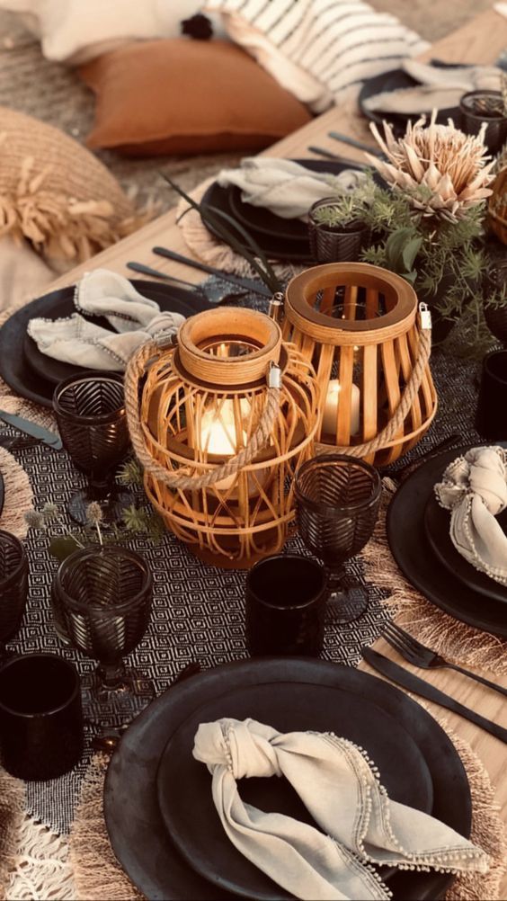 A table set for a picnic with plates , glasses , and candles.