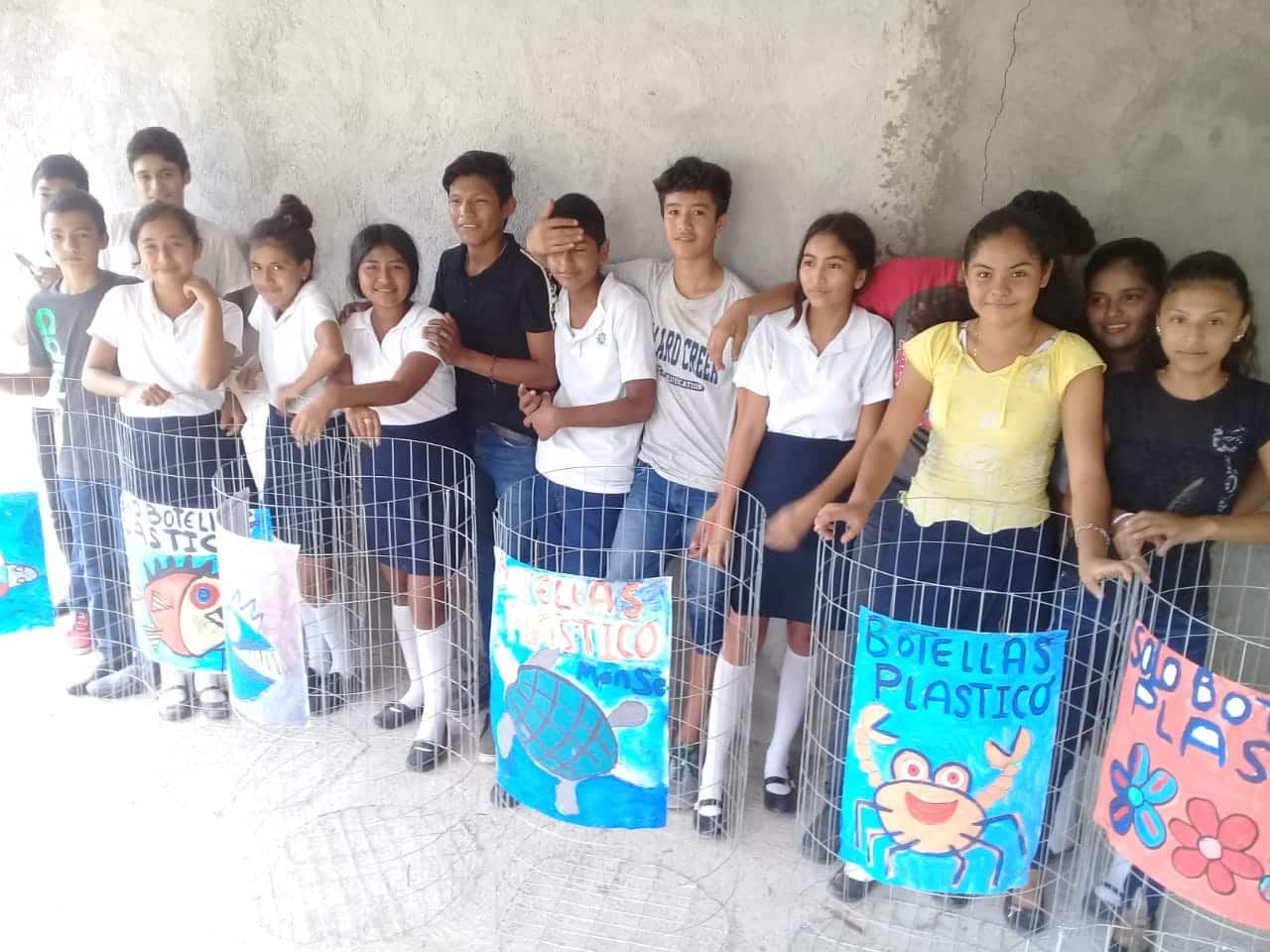 A group of children standing in front of a fence holding signs that say estrella plastico