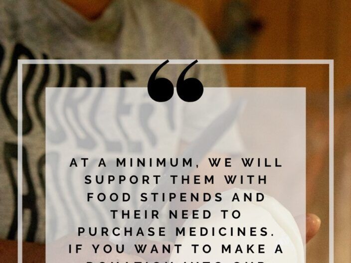 A person holding a sign that says at a minimum we will support them with food stipends and their need to purchase medicines