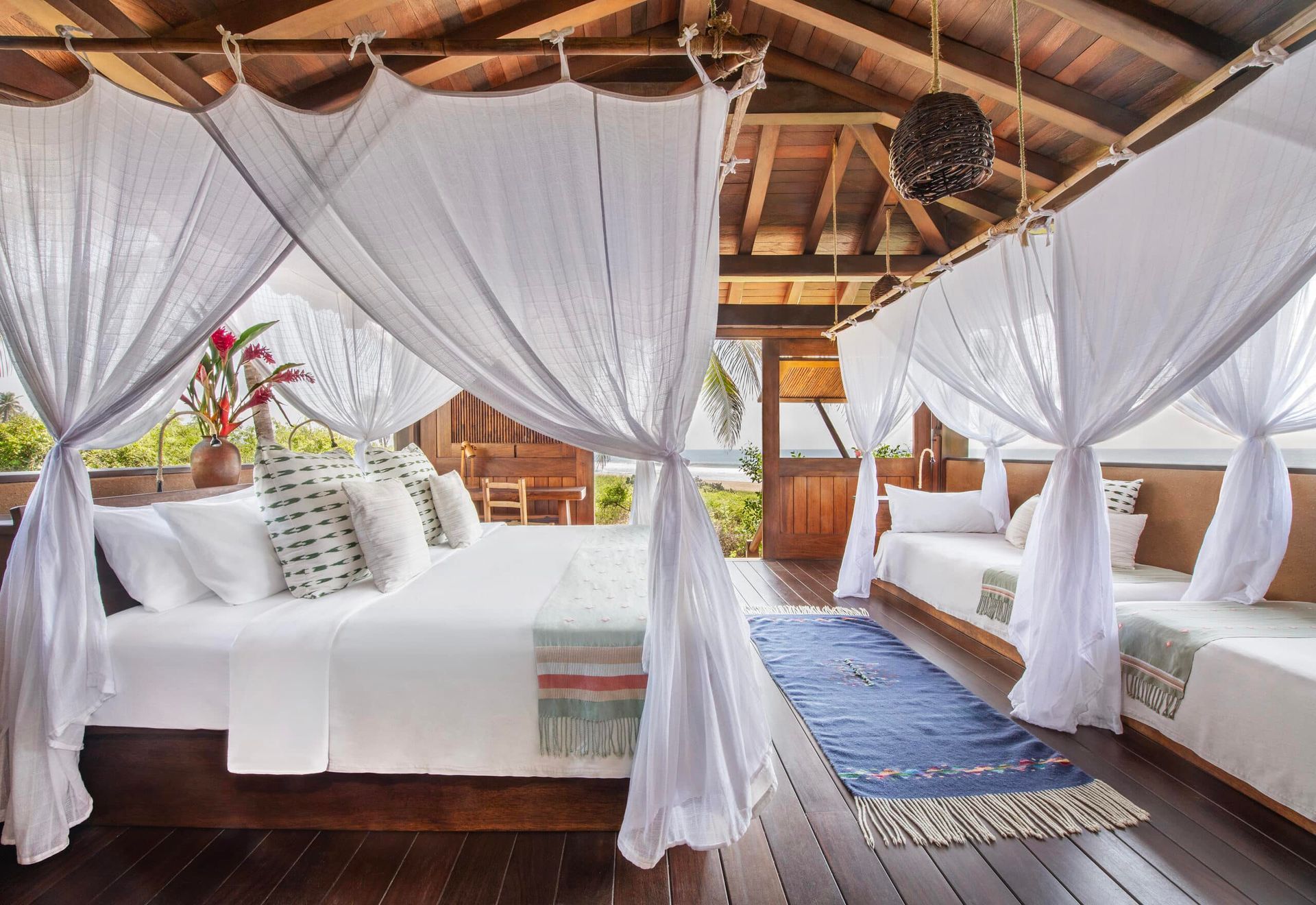 A bedroom with a canopy bed , two beds and a rug.