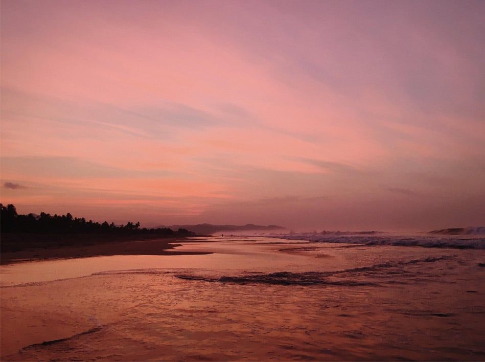 A sunset over a body of water with a pink sky