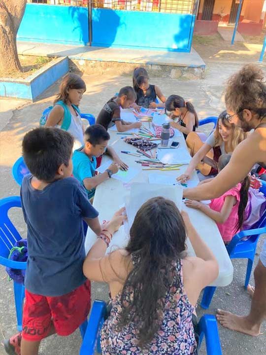 A group of children are sitting around a table drawing.