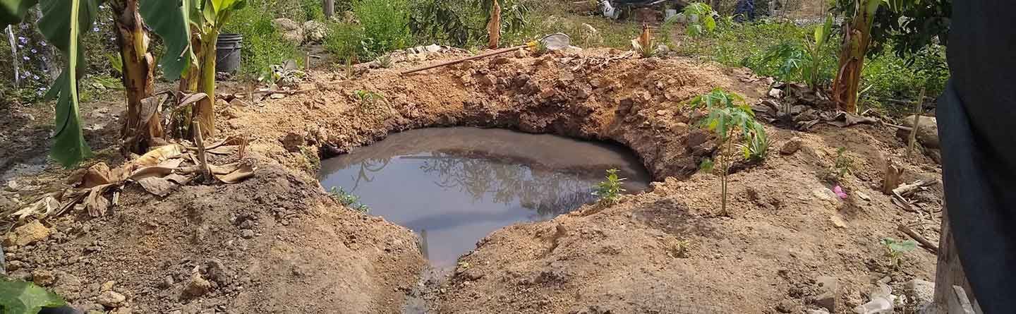 A large puddle of water is in the middle of a dirt field.