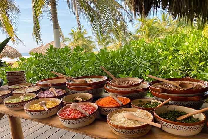 A table topped with bowls of food and spoons.