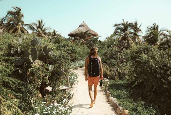 A man with a backpack is walking down a path.