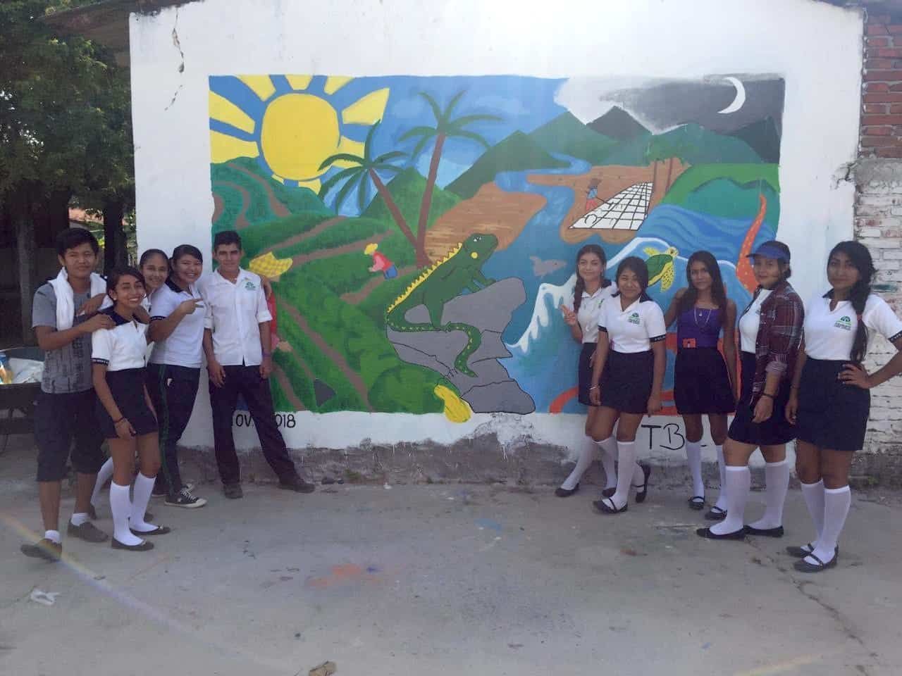 A group of people standing in front of a wall with a painting on it
