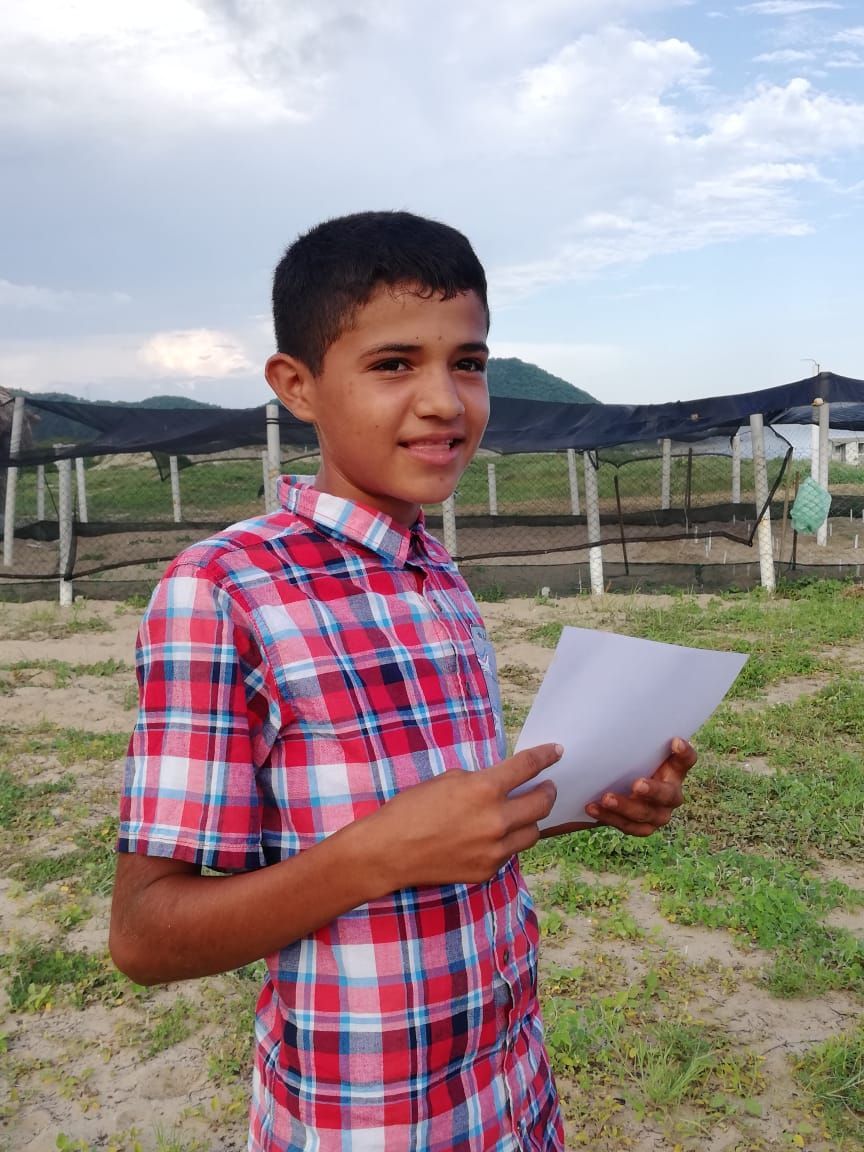 A young boy in a plaid shirt is holding a piece of paper