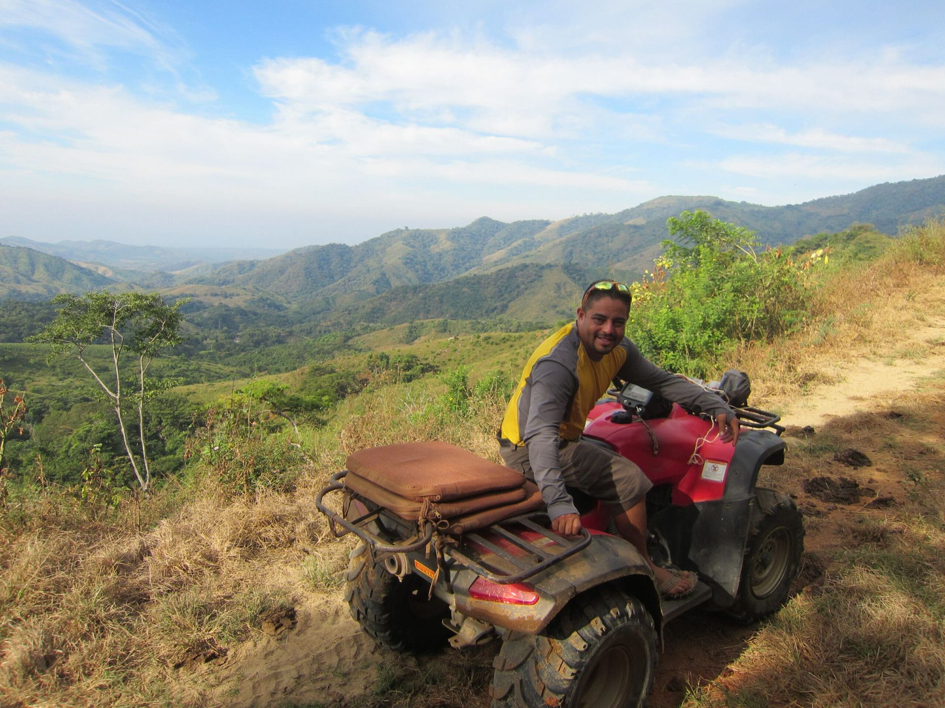 A man is sitting on a red atv on top of a hill.