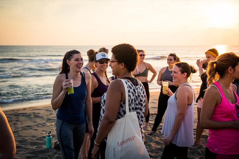 A group of women are standing on a beach talking to each other.