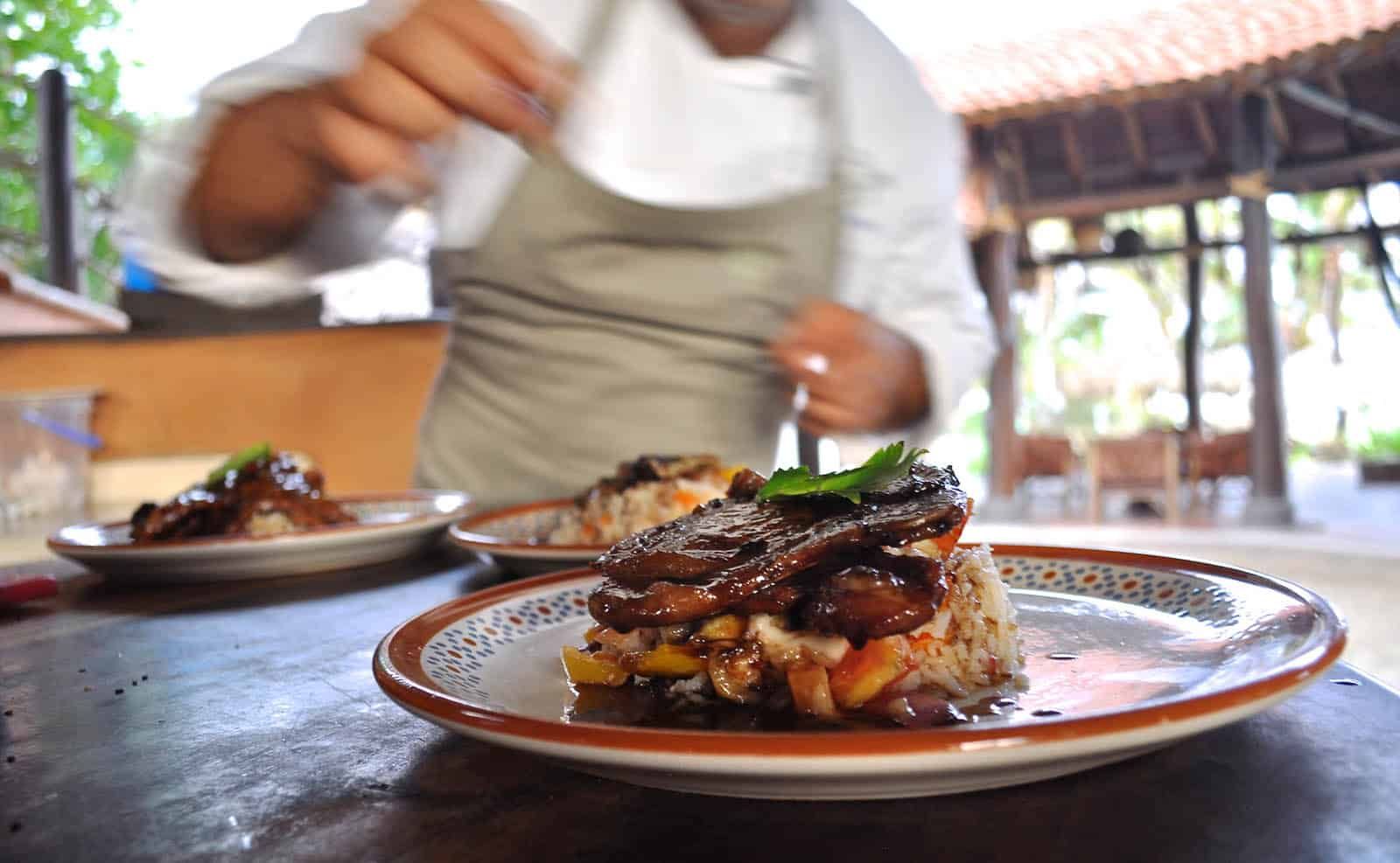 A chef is preparing a plate of food on a table.