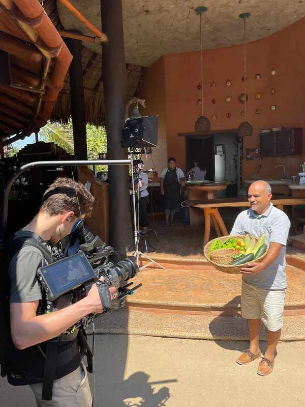 A man is holding a basket of food in front of a cameraman.