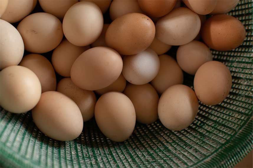 A bunch of brown eggs are in a green bowl