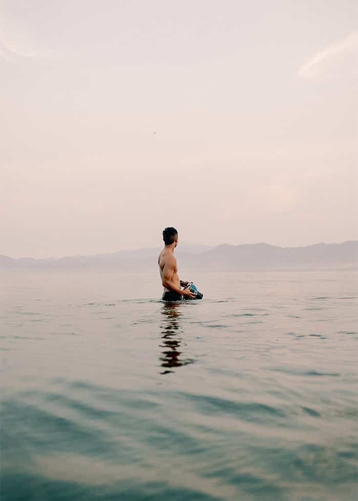 A man is sitting in the middle of a body of water.