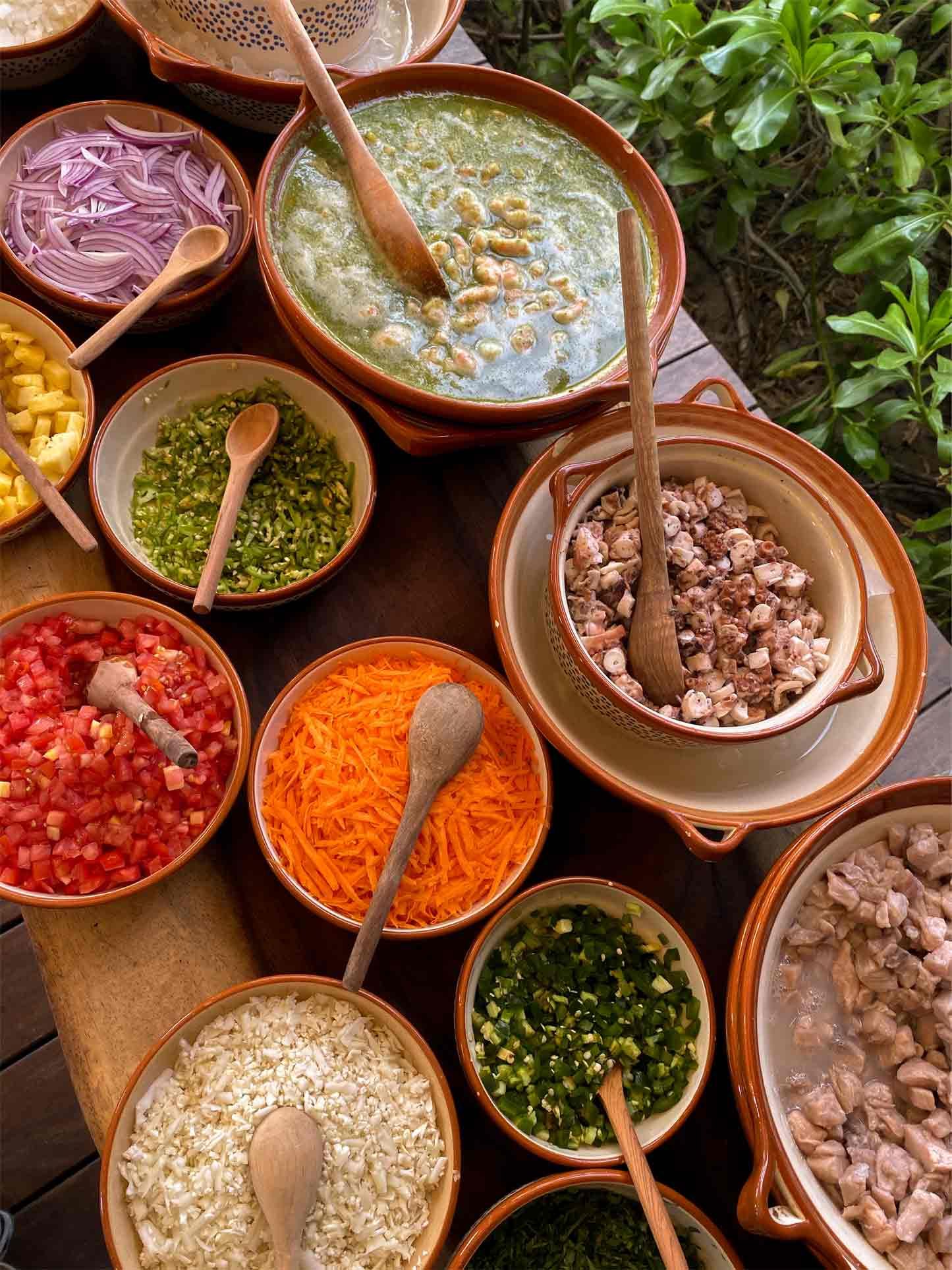 A table topped with bowls of food and spoons.