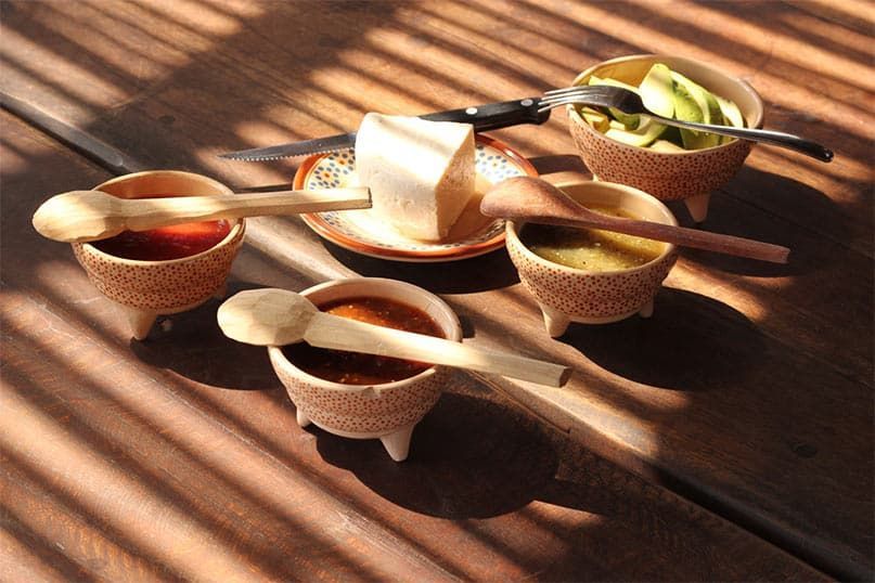 A wooden table with bowls of food and wooden spoons