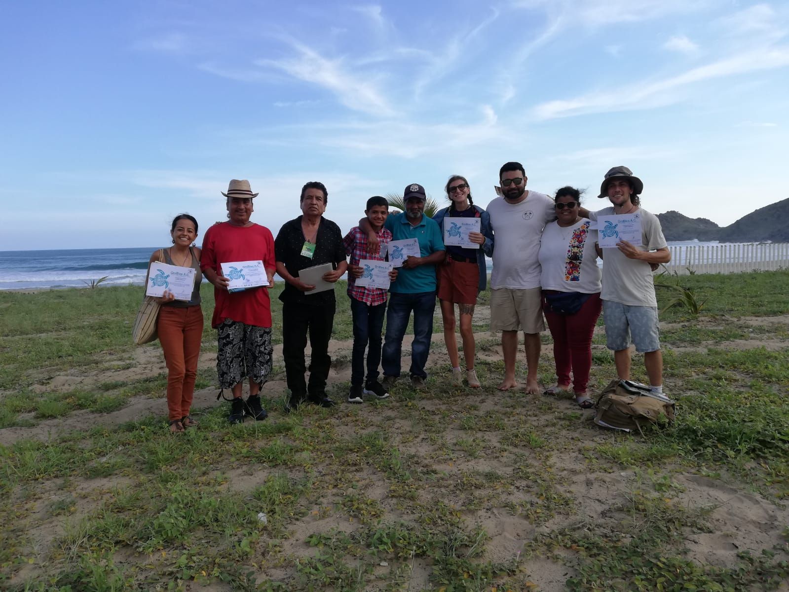 A group of people are posing for a picture on a beach.