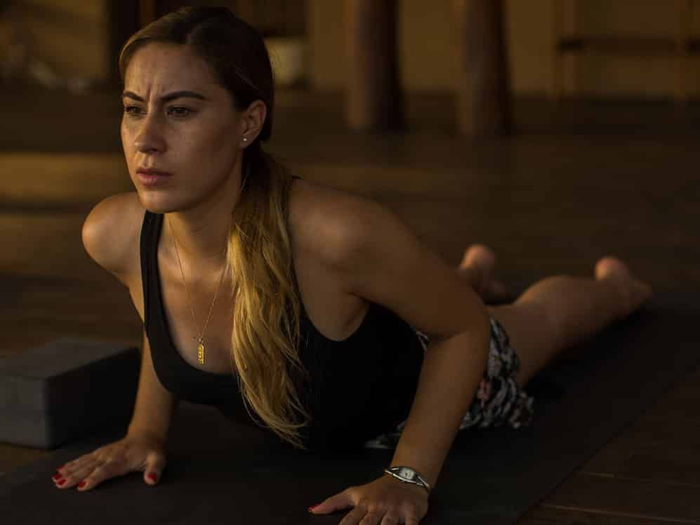 A woman is laying on a yoga mat in a dark room.