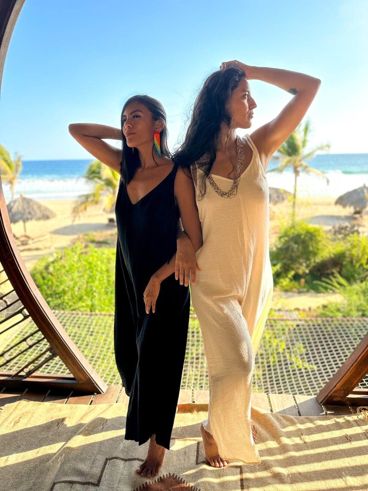Two women are standing next to each other on a balcony overlooking the ocean.